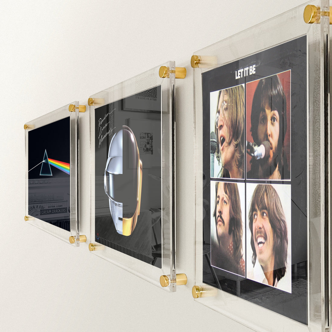 Three albums being displayed in plexiframes with Gold wall mounts.